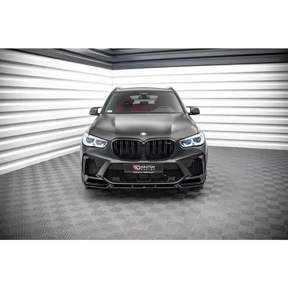 Frontspoiler på Bmw X5M F95 V.1 vist forfra med LED-lykter og stor svart grill innendørs.