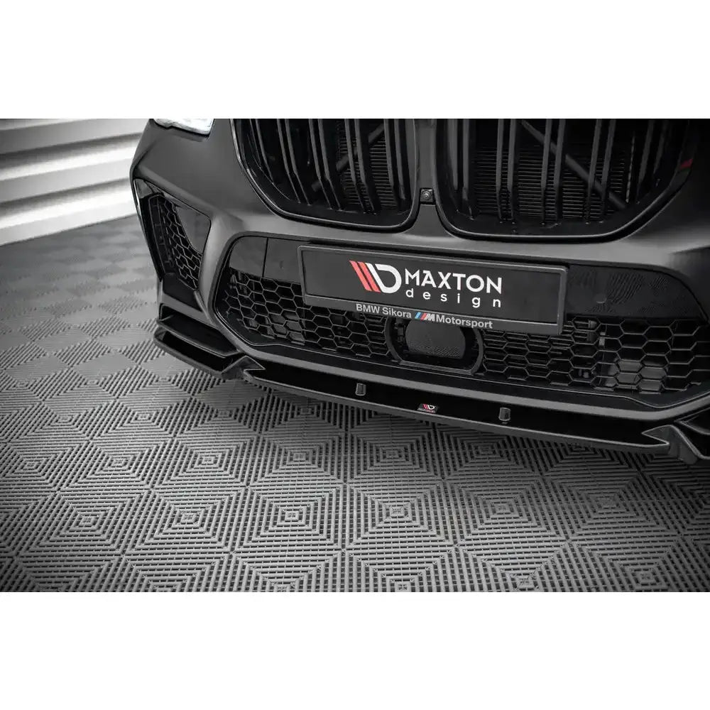 Front lip til BMW X5M F95 V.1 i sort blank finish, montert foran med synlig grill og luftinntak.