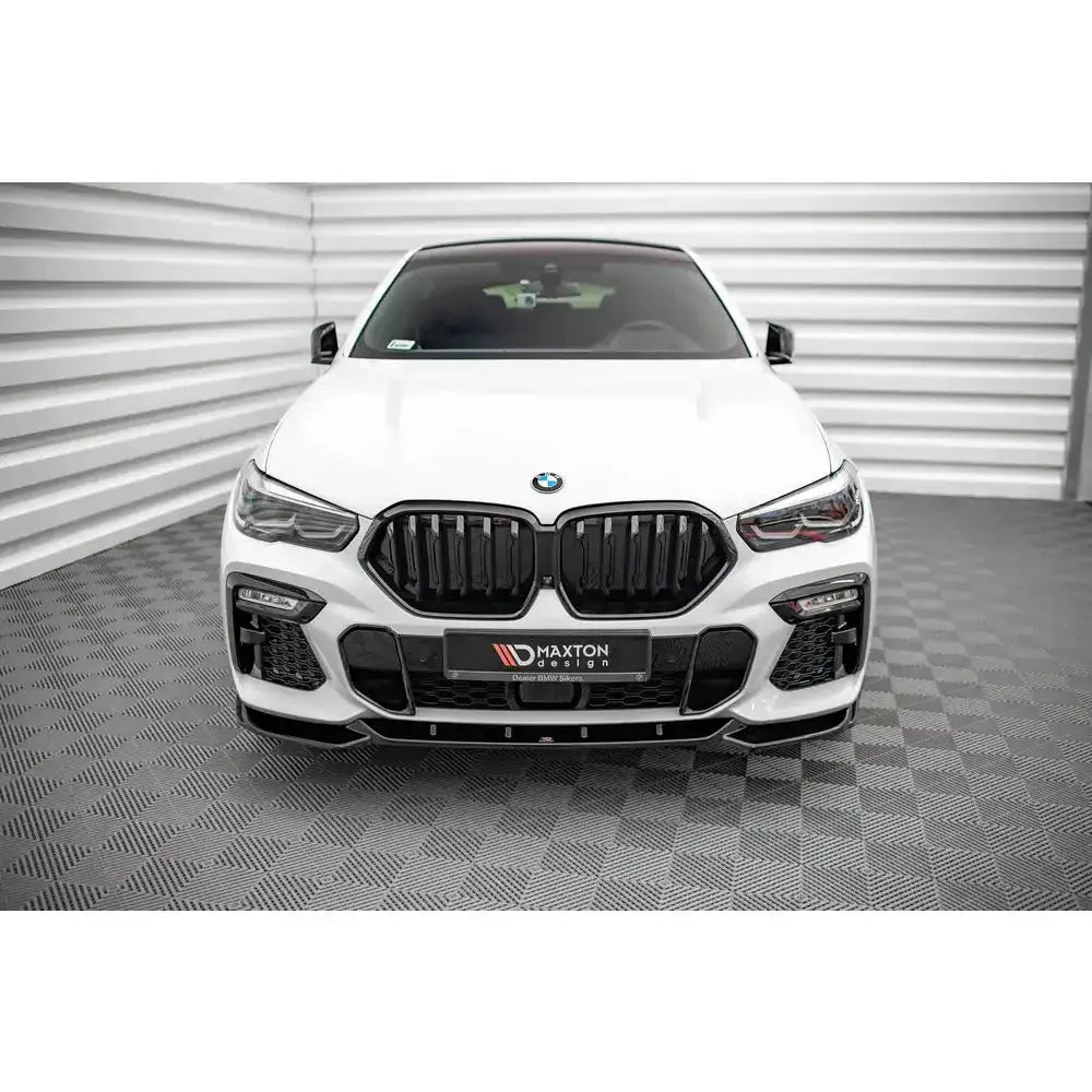 Frontspoiler på hvit BMW X6 M-Pack G06 med svart grill og sportslige luftinntak, sett forfra.