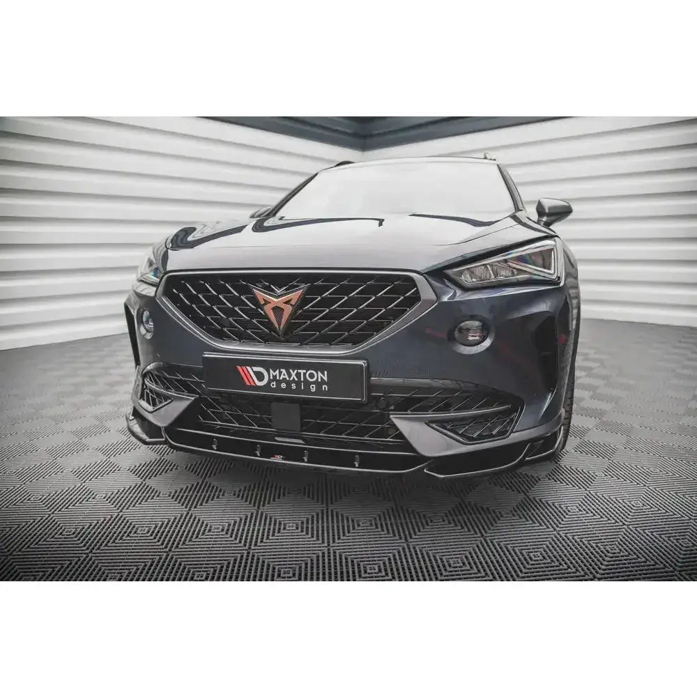 Frontsplitter på sort Cupra Formentor med kobberfarget emblem og sporty detaljer i lyst rom.