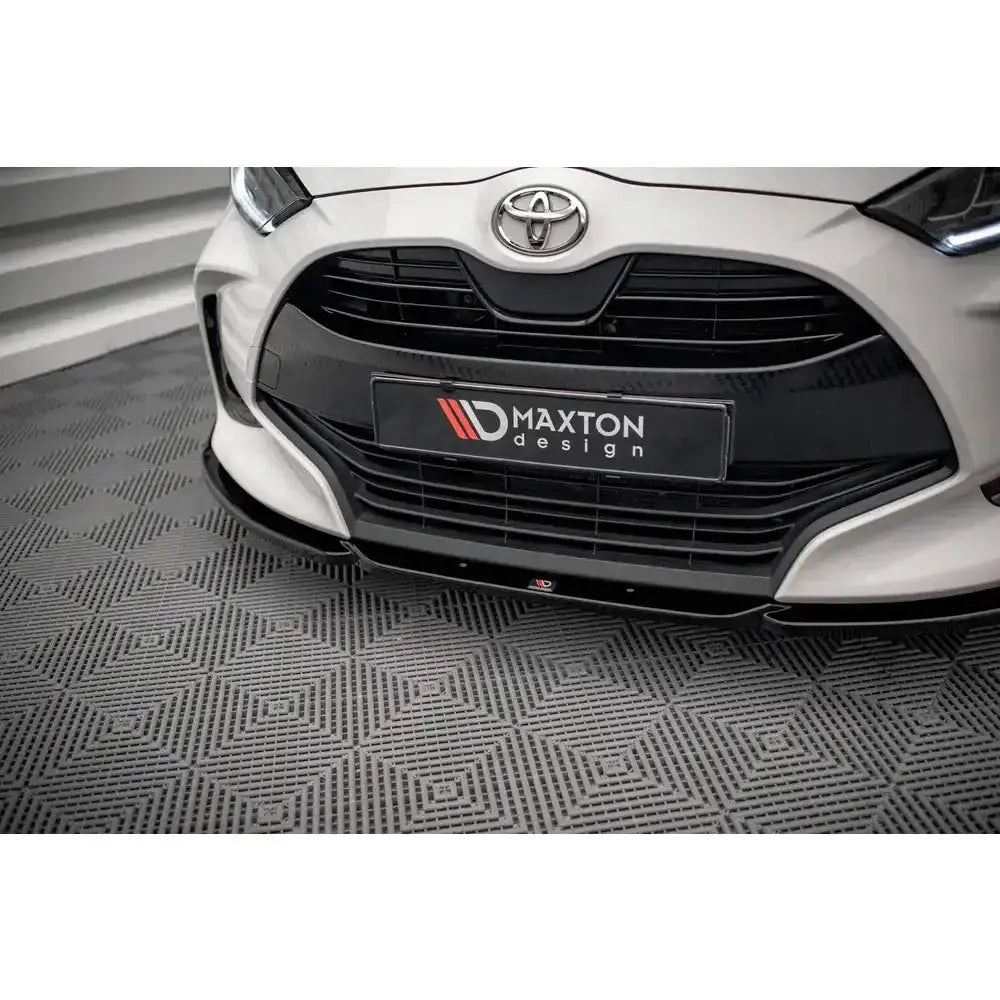 Frontsplitter på hvit Toyota Yaris Mk4 med sort grill og frontleppe, sett fra skrå vinkel.