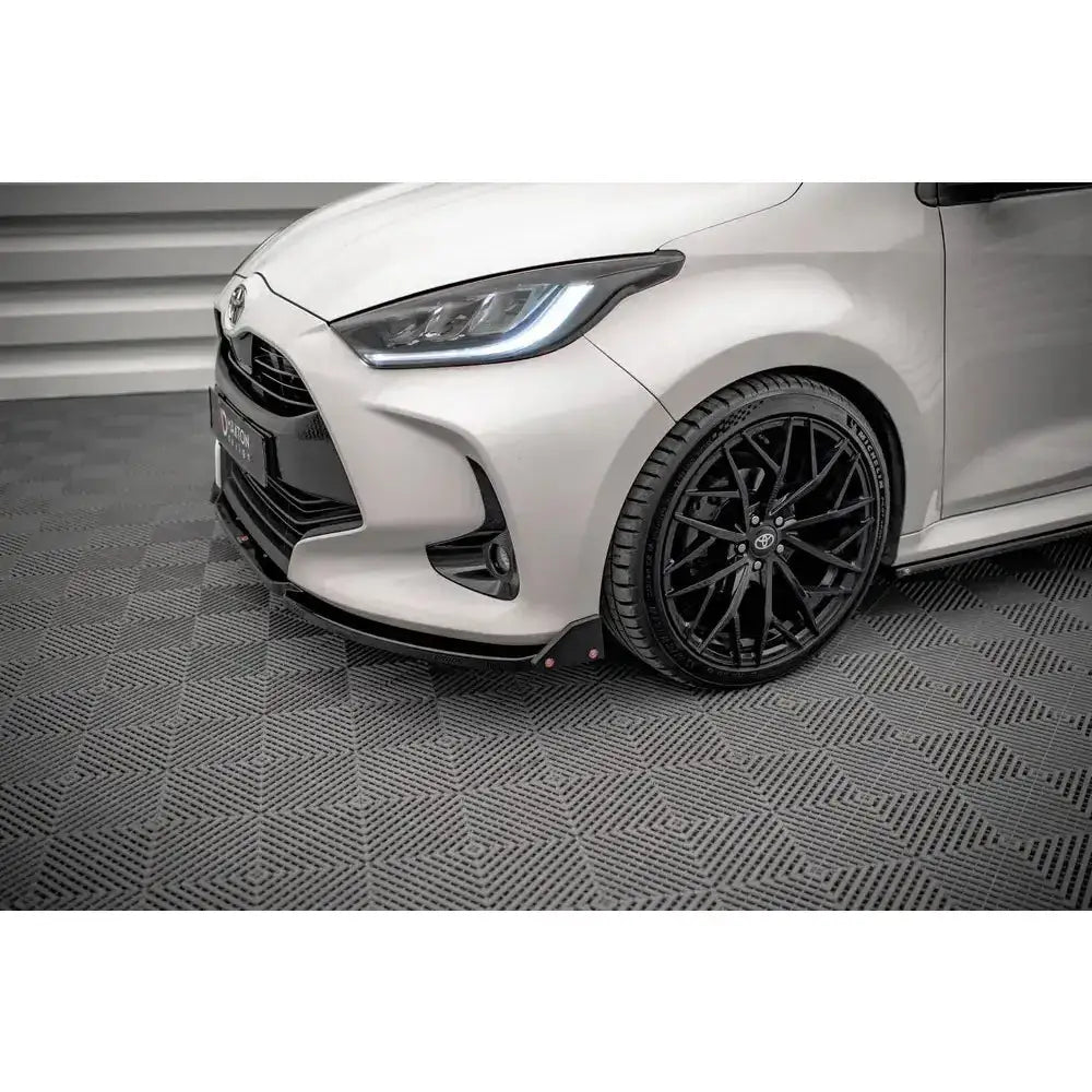 Front splitter på Toyota Yaris Mk4 med svarte lettmetallfelger sett fra skrått frontperspektiv.