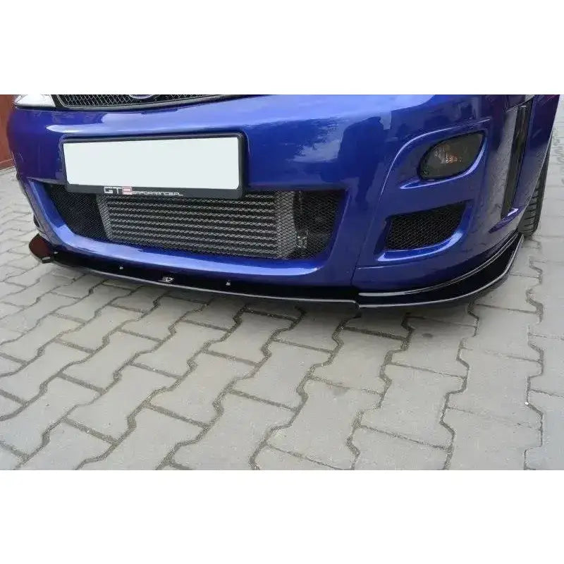 Frontsplitter på blå Ford Focus Mk1 RS sett forfra med sort leppe og metallgitter, parkert på stein.
