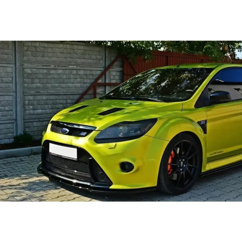 Frontsplitter på lys grønn Ford Focus Mk2 RS med svarte felger og oransje bremsekalipere utendørs.