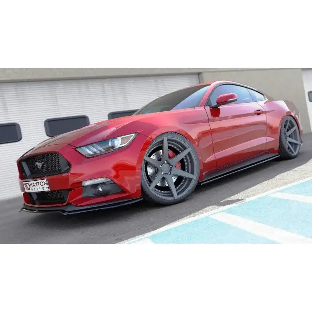 Frontsplitter på rød Ford Mustang Mk6 med grå felger, sort grill og industribygg i bakgrunnen.