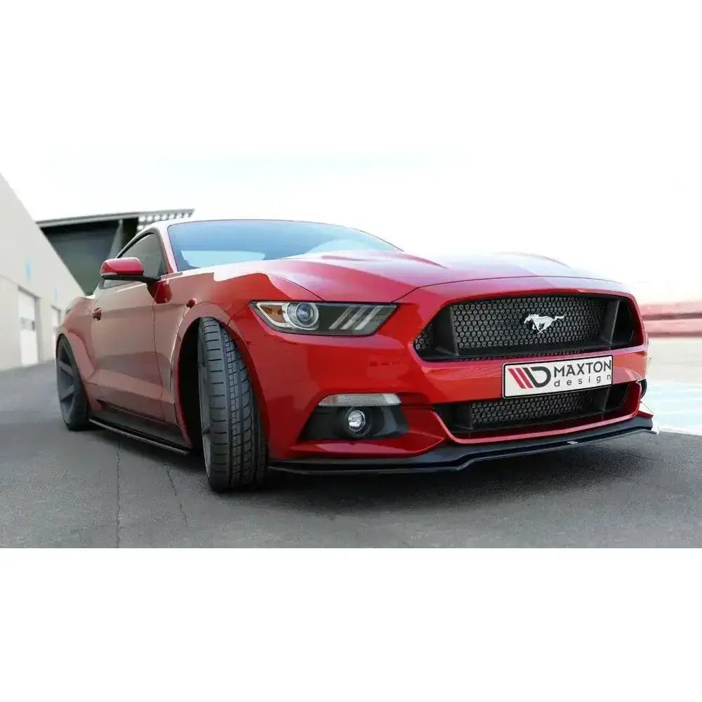 Front lip på rød Ford Mustang Mk6 med brede dekk, sort grill og lav frontspoiler foran garasje.