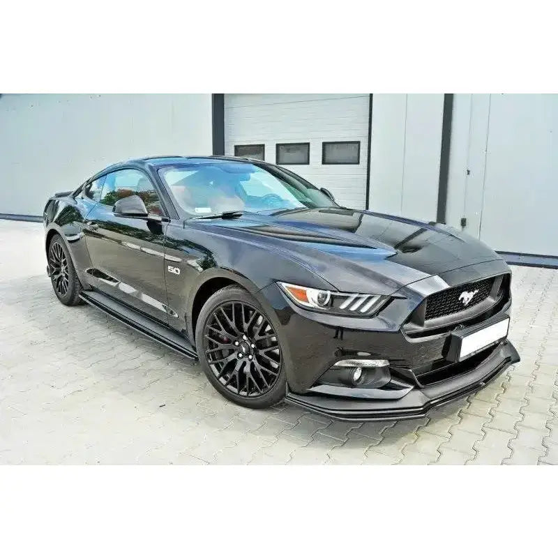Frontspoiler på Ford Mustang Mk6 GT vist fra skrå vinkel med sorte felger og industriport i bakgrunnen.