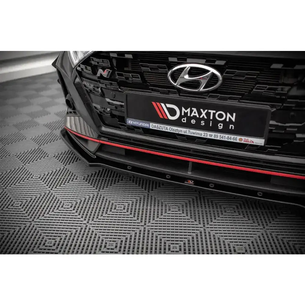 Front lip til Hyundai I20 N Mk3 V.1, nærbilde av svart spoiler med rød stripe og karbonlignende detaljer.