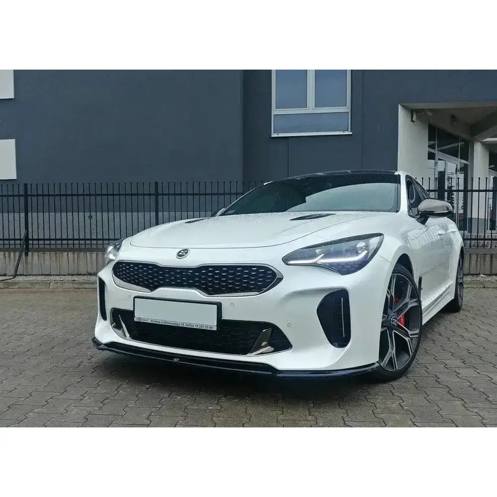 Frontspoiler på hvit Kia Stinger GT med sorte detaljer og rød bremsekaliper, parkert utendørs.
