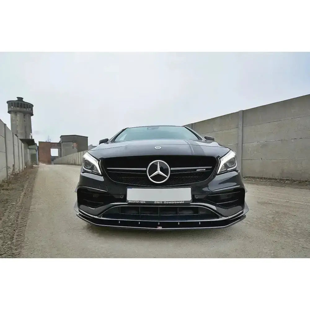 Frontsplitter på Mercedes Cla A45 AMG C117 Facelift med sorte og kromdetaljer parkert mellom betongmurer.