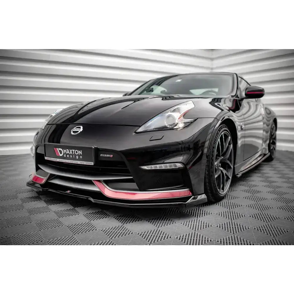 Front lip på Nissan 370Z Nismo Facelift 14-20 med røde detaljer og mørke felger, sett skrått forfra innendørs.