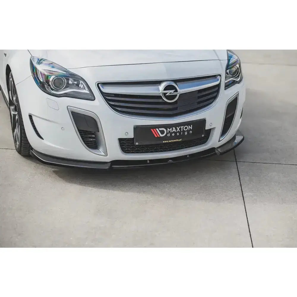 Front splitter på hvit Opel Insignia MK. 1 OPC Facelift, sort plast mot lys betong.