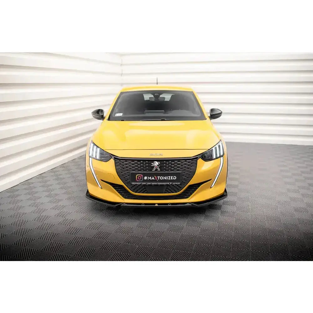Frontspoiler på Peugeot 208 GT Mk2 sett forfra, med sort grill og LED-lys, innendørs bakgrunn.