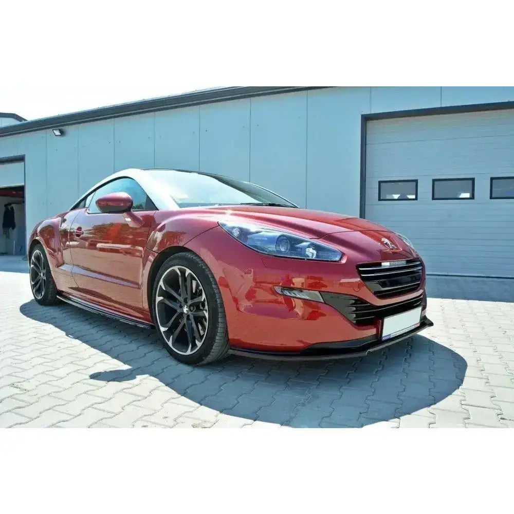 Frontspoiler på Peugeot RCZ Facelift V.1, rød bil med sorte felger parkert foran industribygg.