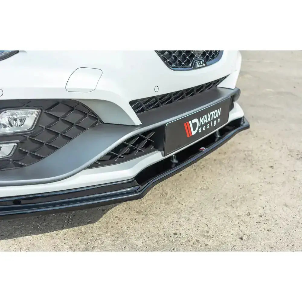 Frontsplitter til Renault Megane IV Rs i sort blank plast montert under hvit frontfanger, sett skrått forfra.
