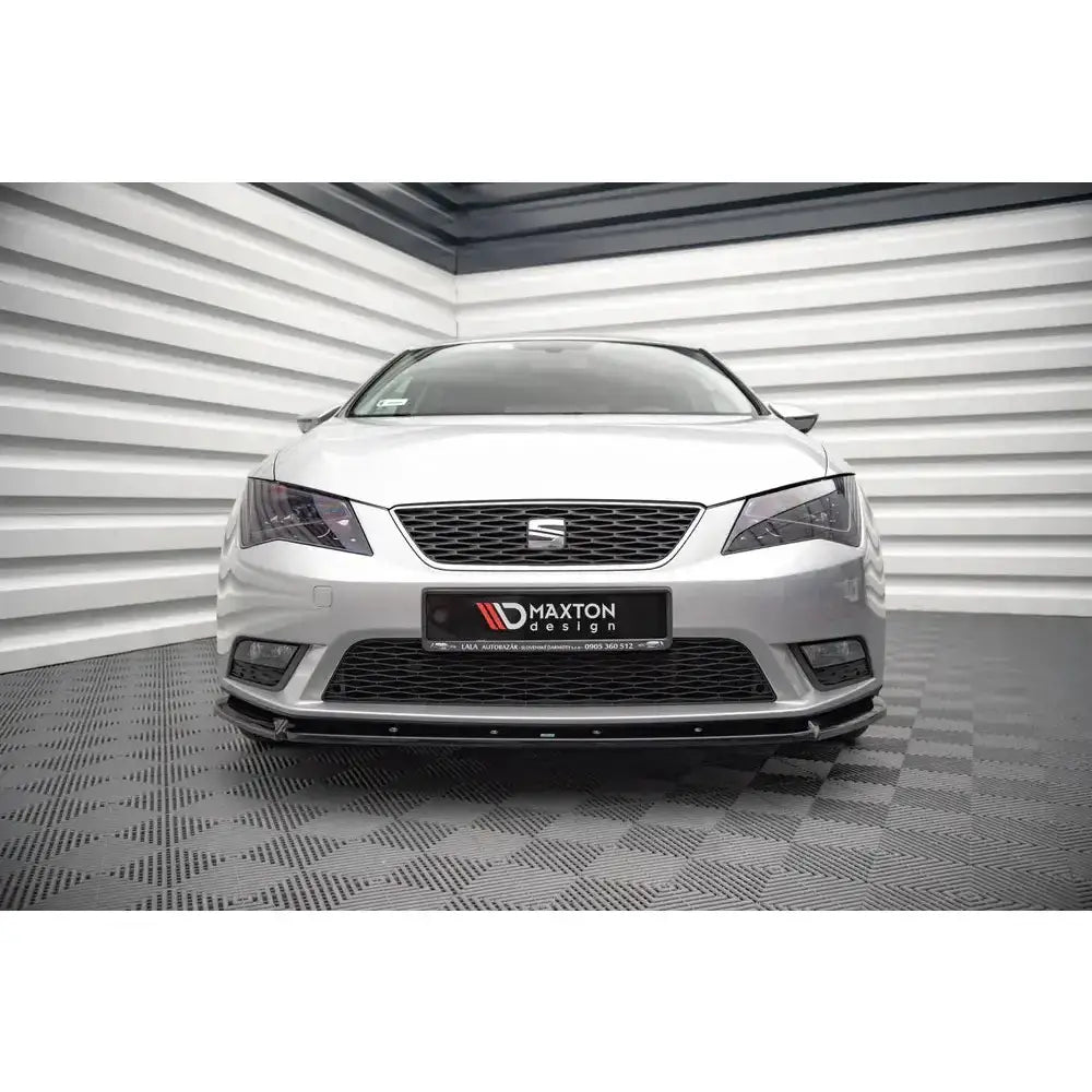 Frontspoiler på Seat Leon Mk3 12-16, sort splitter montert på sølvfarget bil foran lyse veggpaneler.