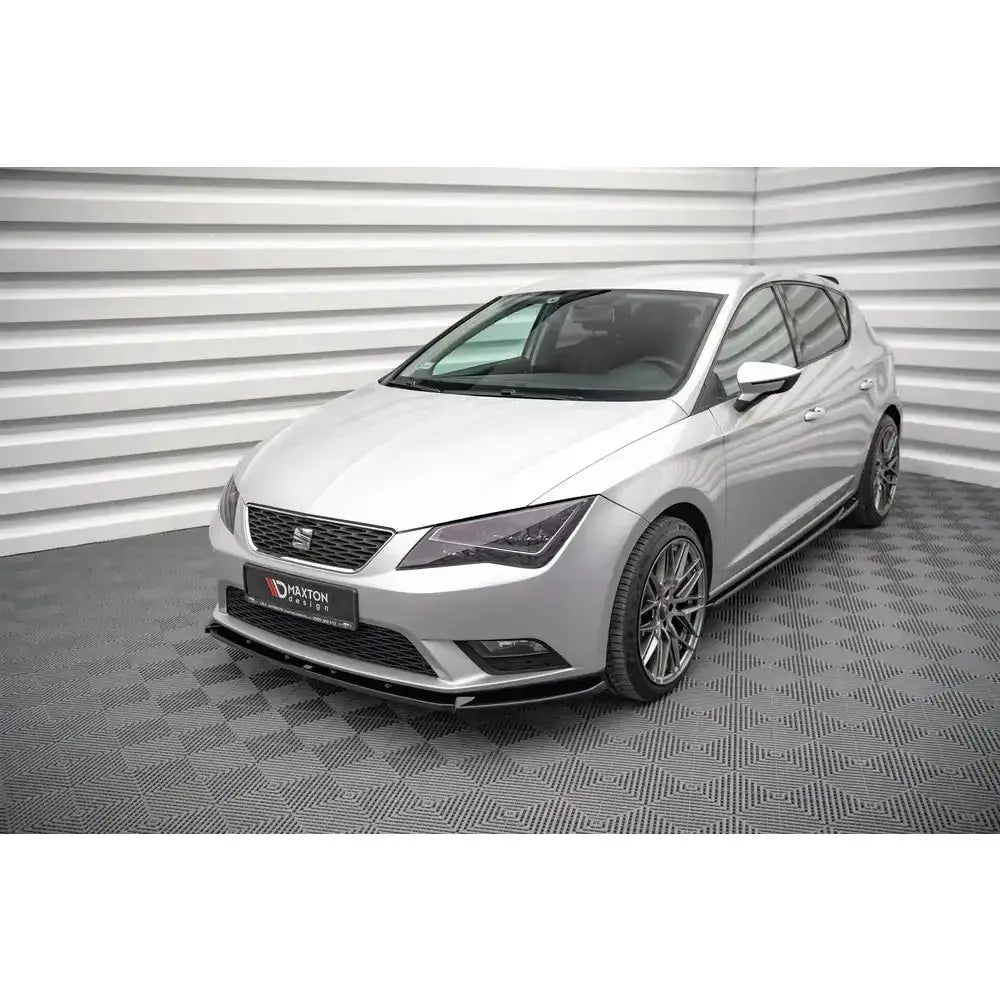 Frontsplitter på Seat Leon Mk3 12-16, sølvfarget bil med lav spoiler og mørke felger, sett skrått forfra.