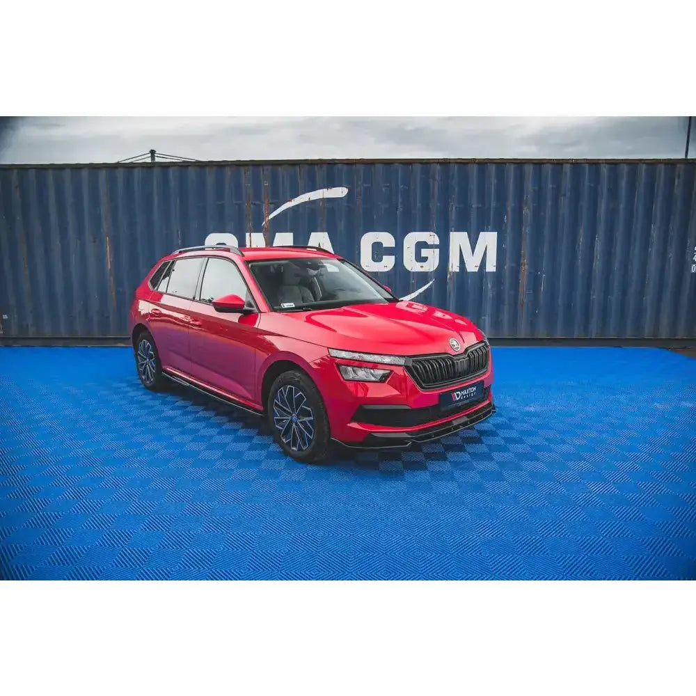 Front lip på rød Skoda Kamiq SUV med sorte detaljer og mørke felger foran mørk container.