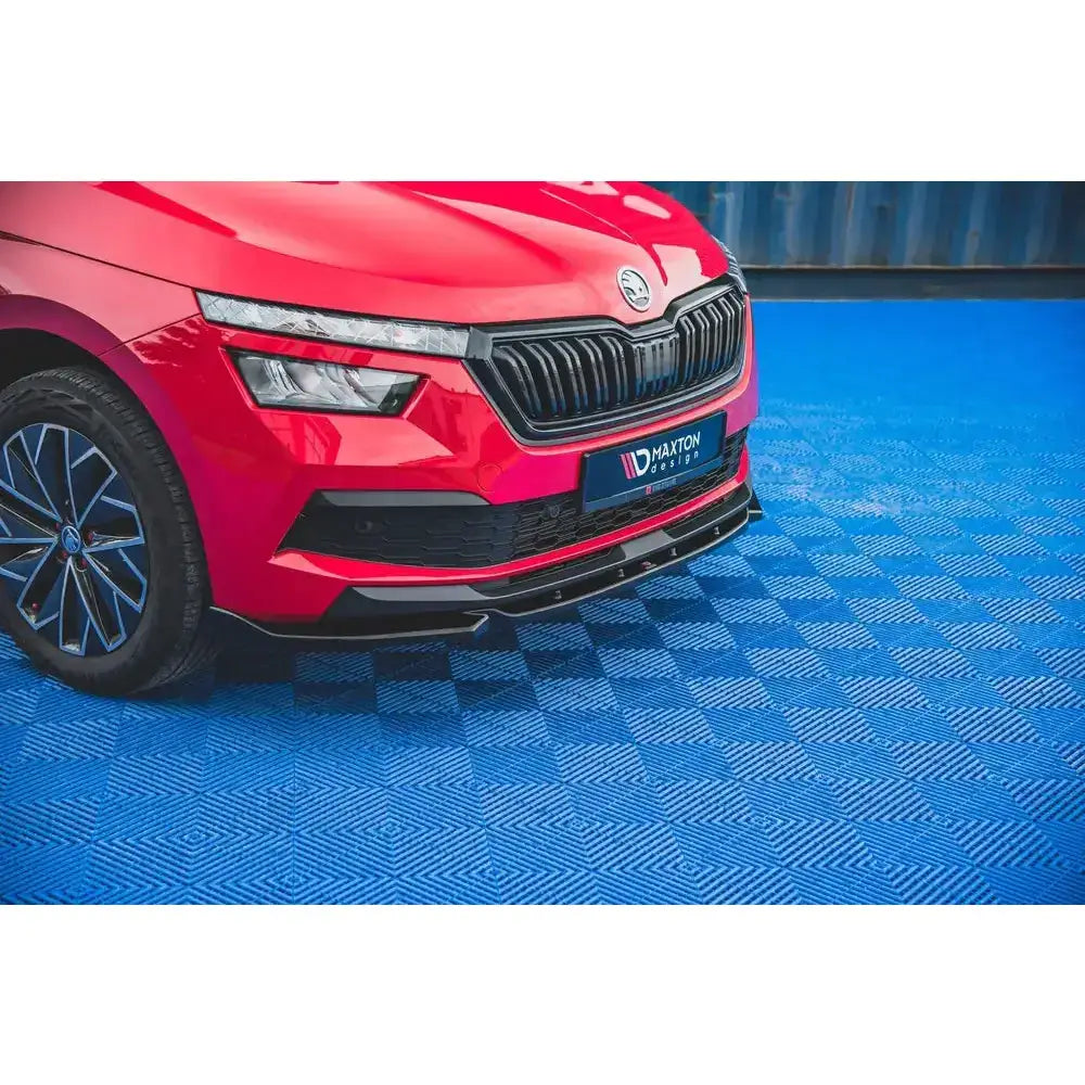 Front splitter på rød Skoda Kamiq med svart grill og spoiler, parkert på blått rutemønstret underlag.