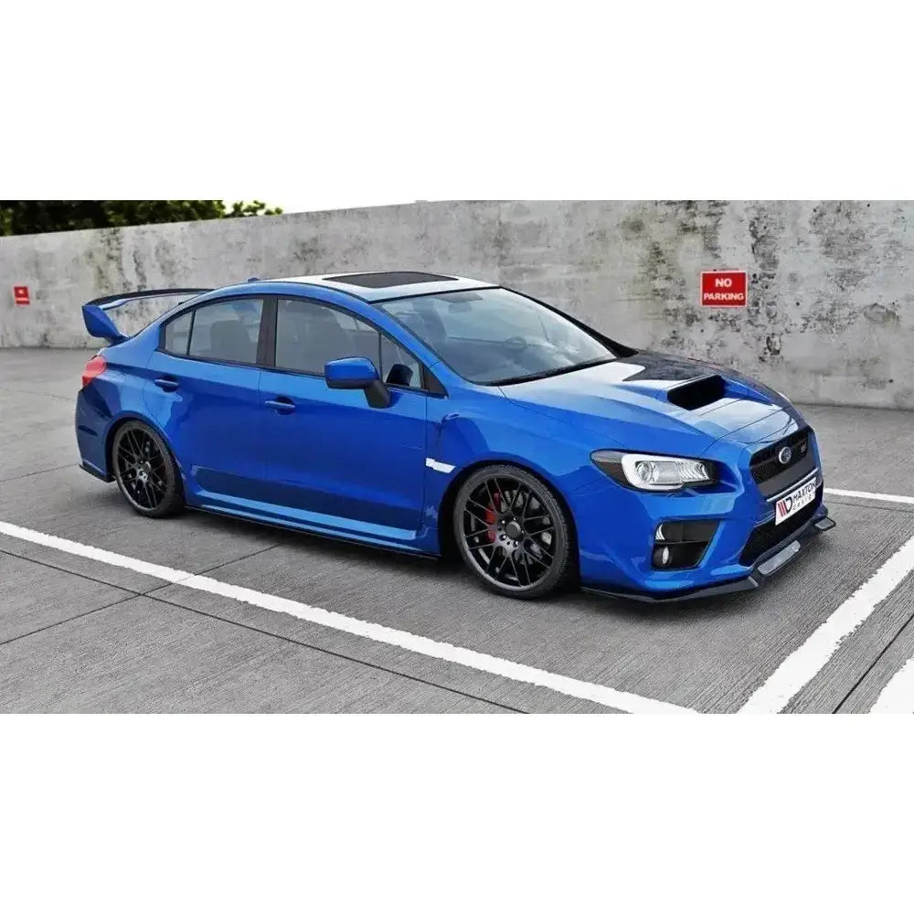 Frontsplitter på blå Subaru Wrx Sti med sorte felger, hekkspoiler og sort panserluke på parkeringsplass.