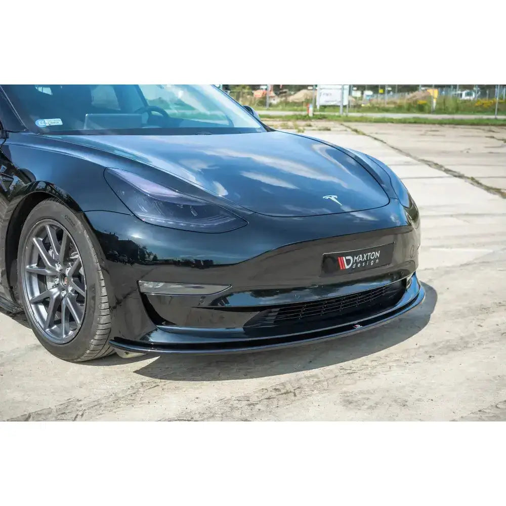 Frontspoiler på sort Tesla Model 3 med blank finish under støtfanger, sett forfra med sporty felger.
