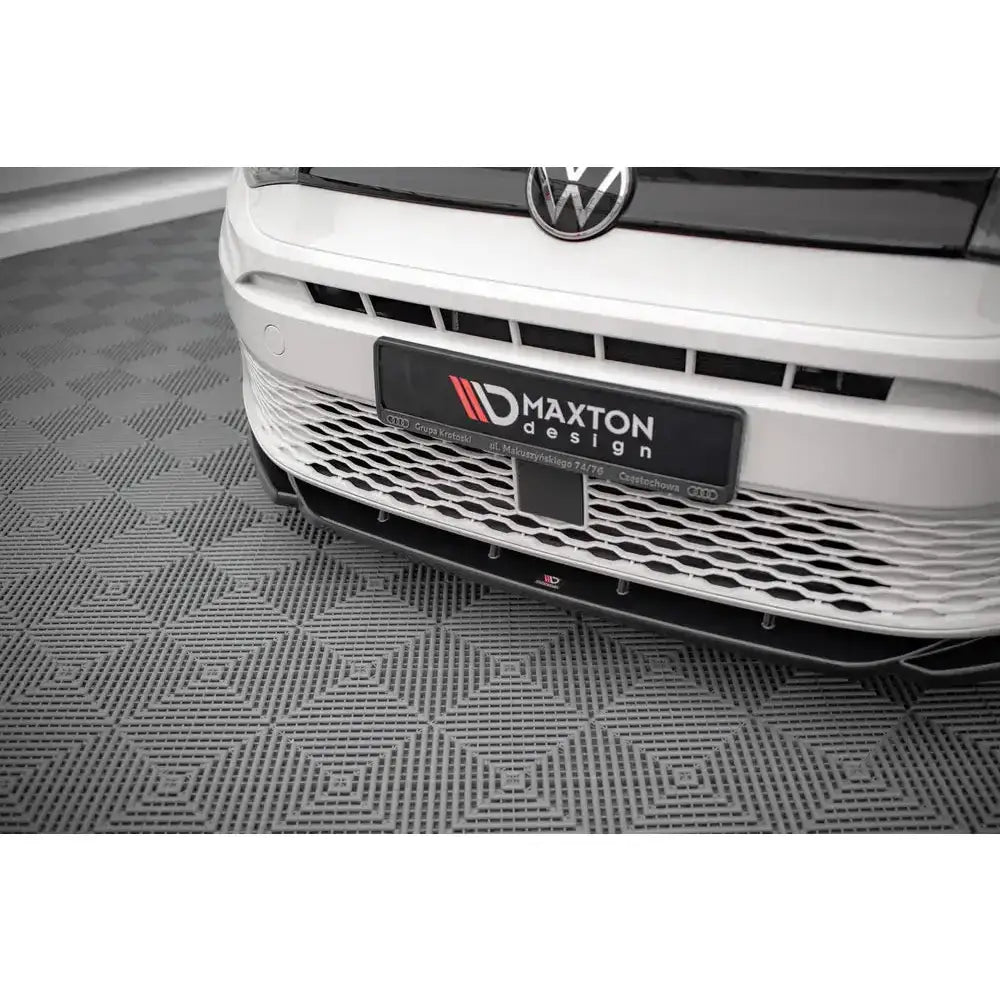 Front lip på Volkswagen Caddy Mk5 med sort splitter, hvit støtfanger og nettinggrill i nærbilde.