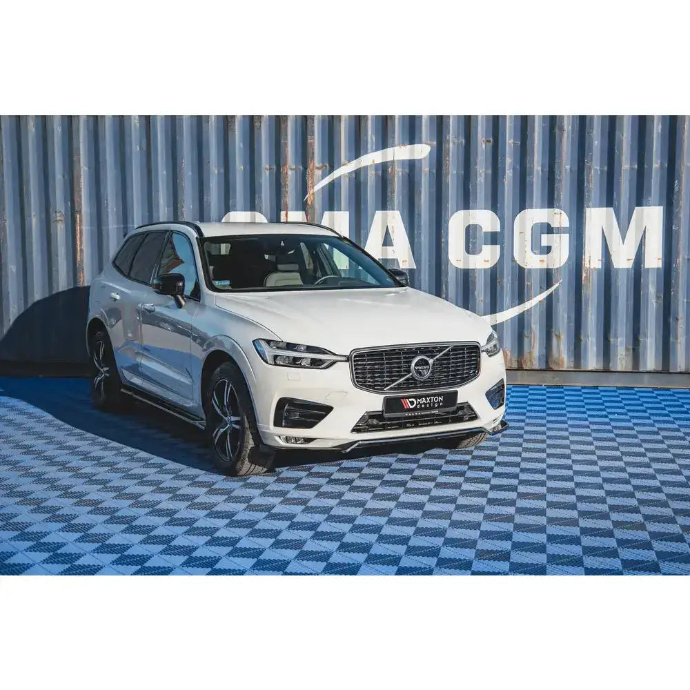 Frontsplitter på hvit Volvo XC60 Mk2 R-Design med sorte detaljer foran blå skipscontainer.