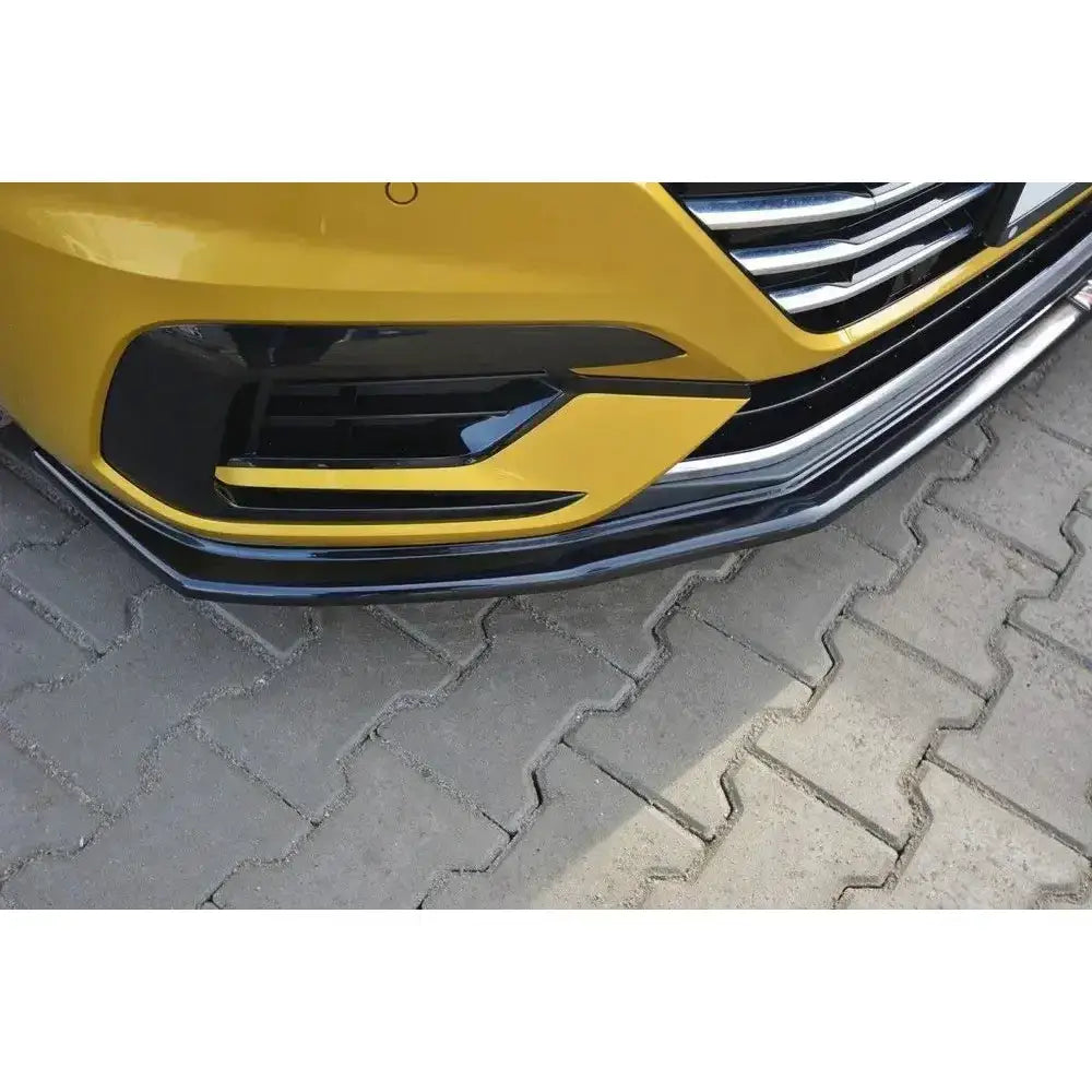 Front lip V.1 VW Arteon nærbilde på gul bil med svarte og sølvdetaljer parkert på grå belegningsstein.