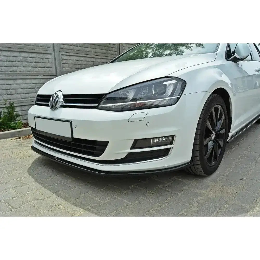 Frontspoiler på VW Golf VII med sort leppe, synlige LED-lys og svarte felger, parkert på brostein.