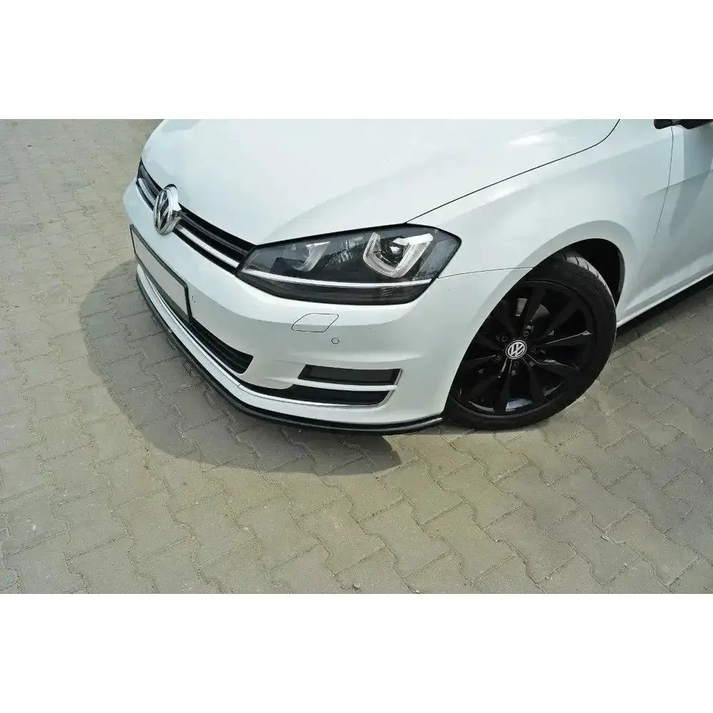 Frontsplitter på hvit VW Golf VII med svarte felger og sort spoiler foran, parkert på brostein.