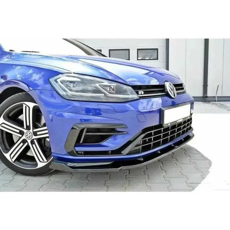 Frontspoiler på VW Golf VII R Facelift med sort frontleppe og sporty felger, sett forfra fra siden.