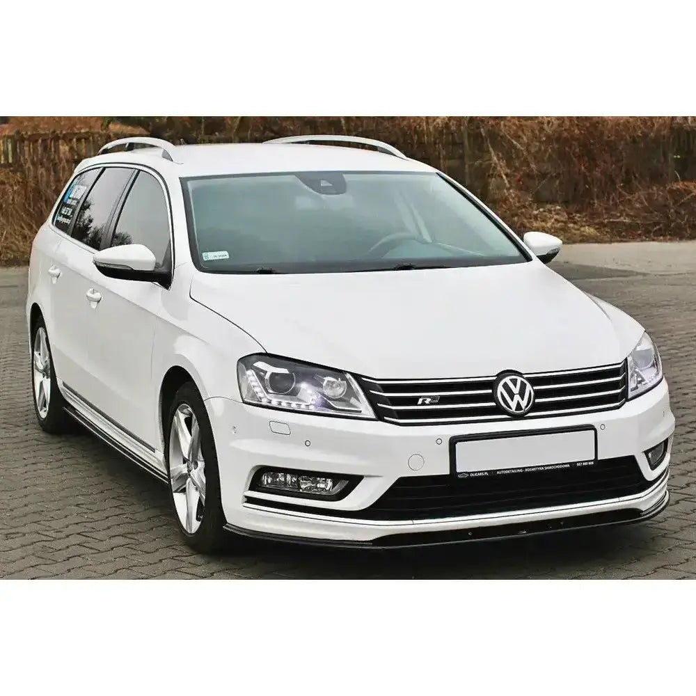 Front lip på hvit VW Passat B7 R-Line stasjonsvogn med sølvdetaljer og LED-lys på brostein.