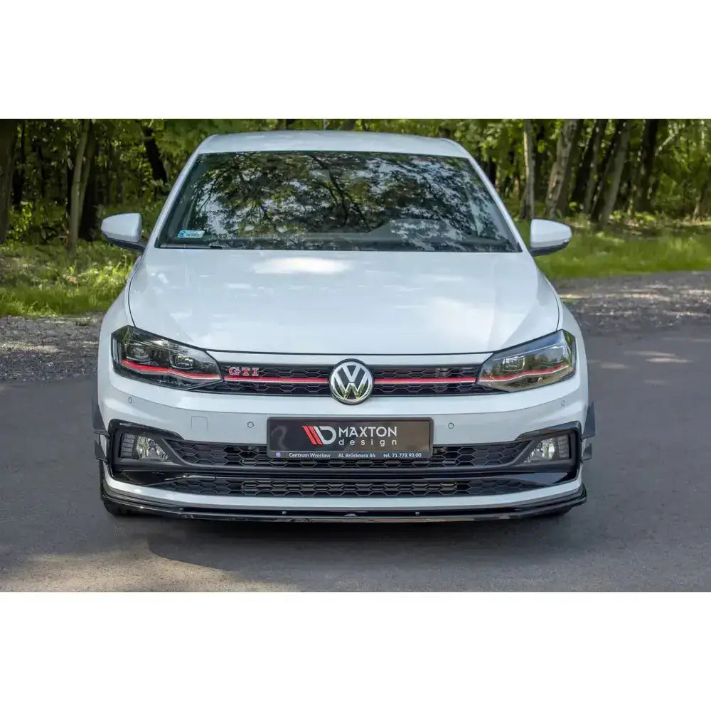 Frontsplitter på hvit VW Polo Mk6 GTI med sorte og røde grilldetaljer, parkert utendørs.