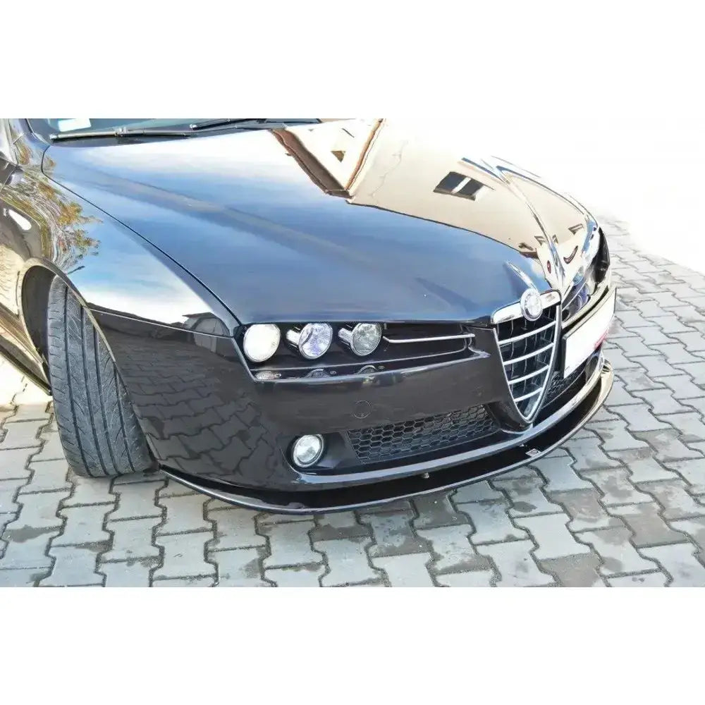 Frontsplitter på Alfa Romeo 159 V.2, sort bil med blank spoiler sett fra skrå vinkel på belegningsstein.