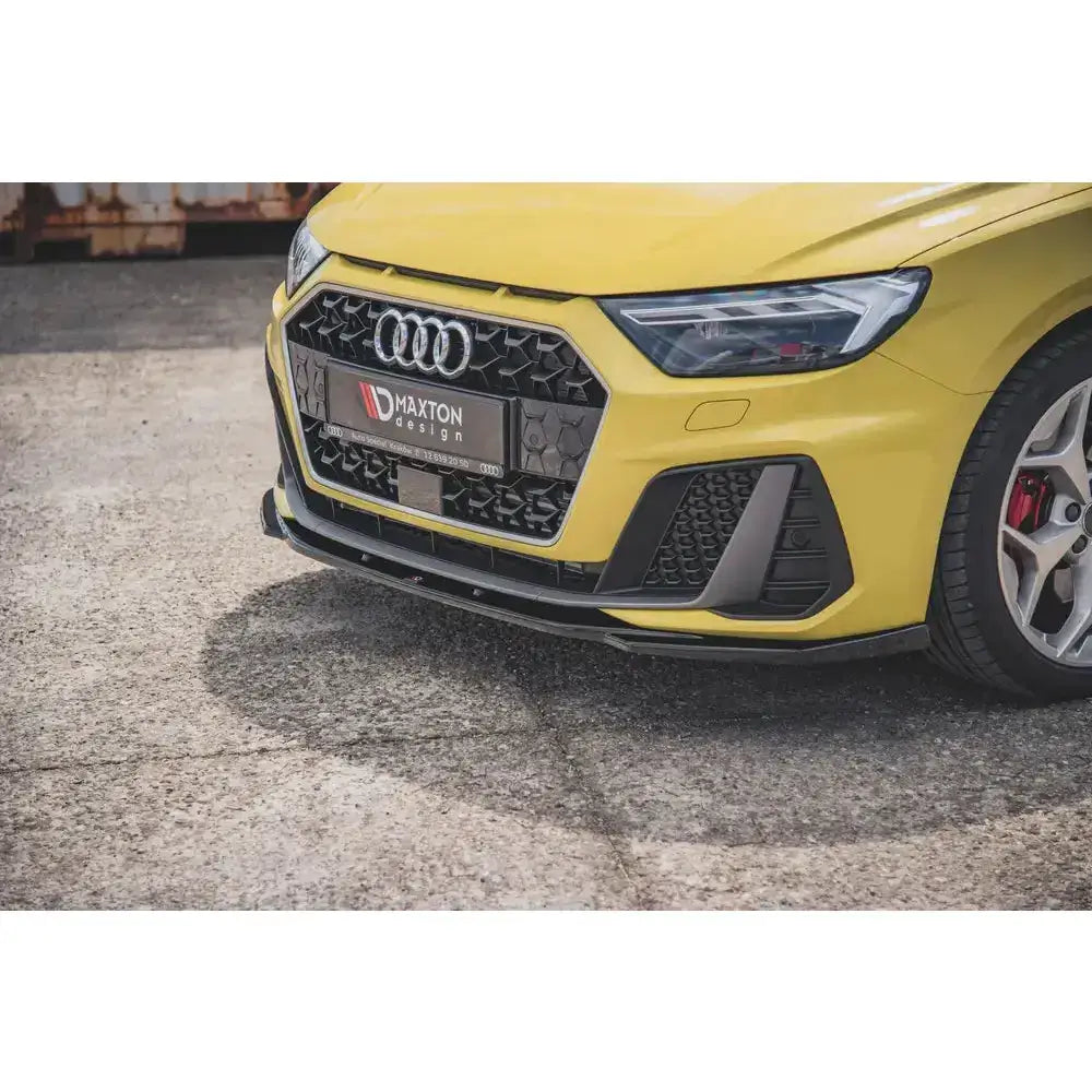 Frontsplitter V.2 Audi A1 S-Line GB i sort plast under gul bilfront med svart grill, sett fra lav vinkel.