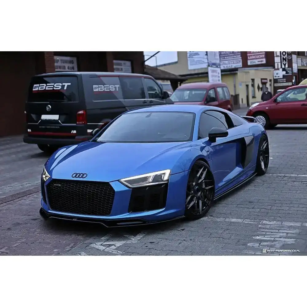 Frontspoiler på blå Audi R8 II med sorte felger og stor sort grill, parkert utendørs.