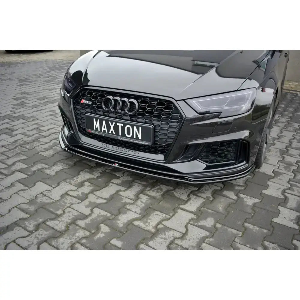 Front splitter Audi RS3 8V V.2 med blank sort finish og markerte luftinntak, sett forfra på steindekke.