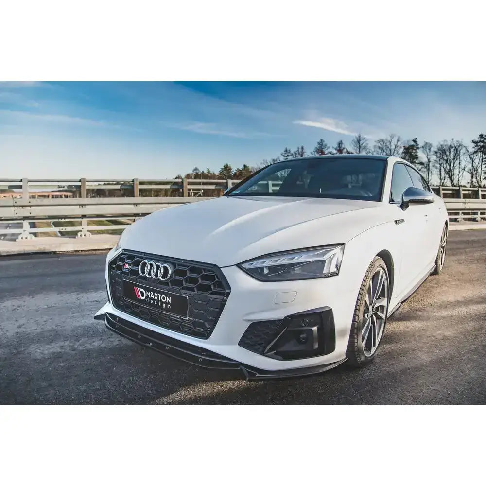 Frontspoiler på Audi S5 F5 Facelift med svart grill, sportsfelger og frontsplitter utendørs.