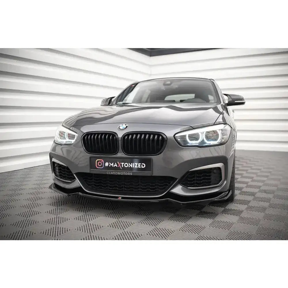 Front lip på grå Bmw 1 F20/F21 M-Power med sorte detaljer, sett rett forfra på rutete gulv.