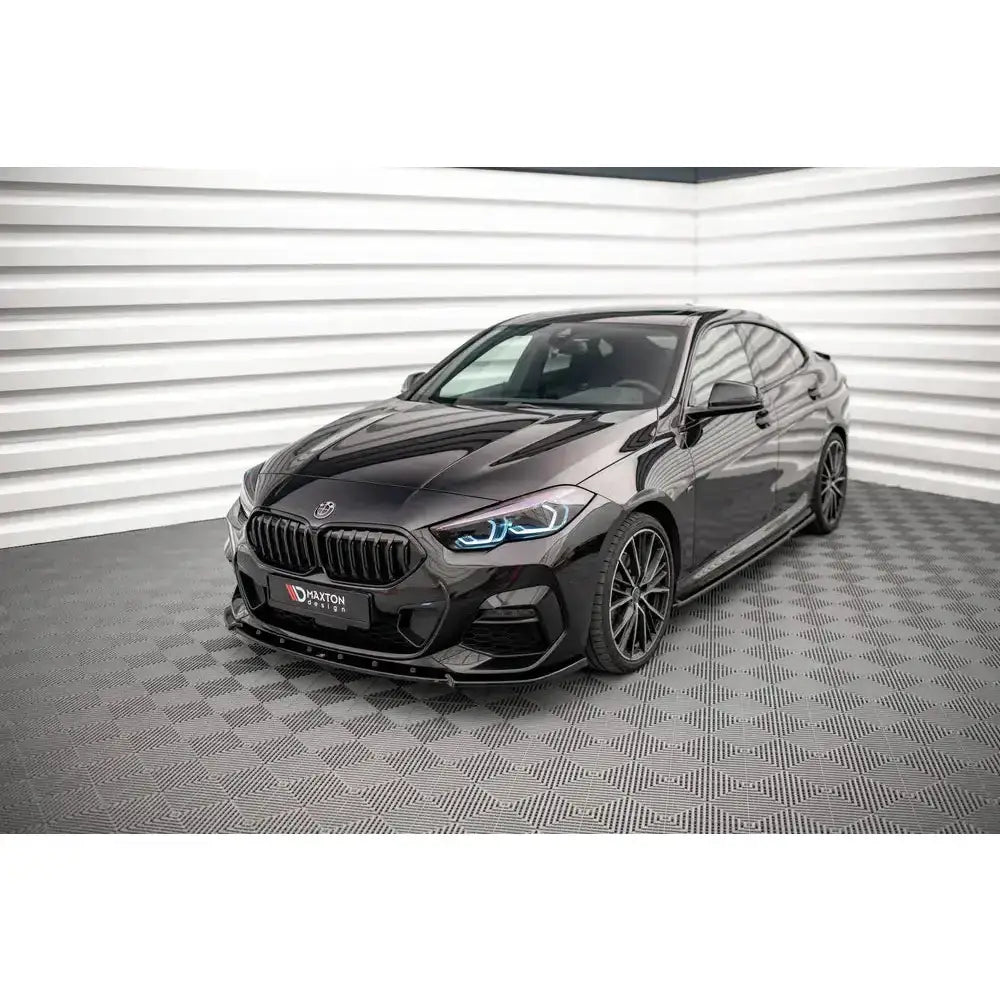 Frontspoiler på BMW 2 Gran Coupe M-Pack med blå LED-lys og store mørke felger i lyst rom.
