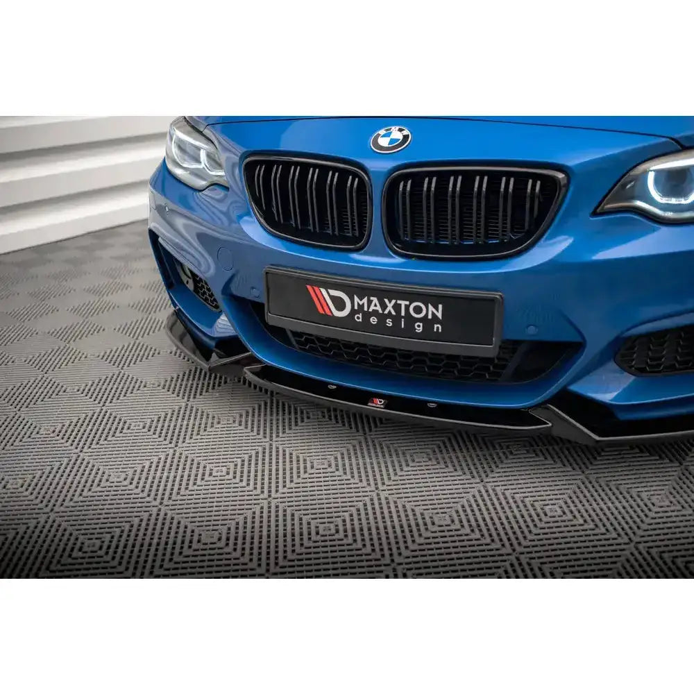 Frontsplitter montert på blå BMW 2 Serie M-Pack F22, sort og blank, vises nær støtfangeren.