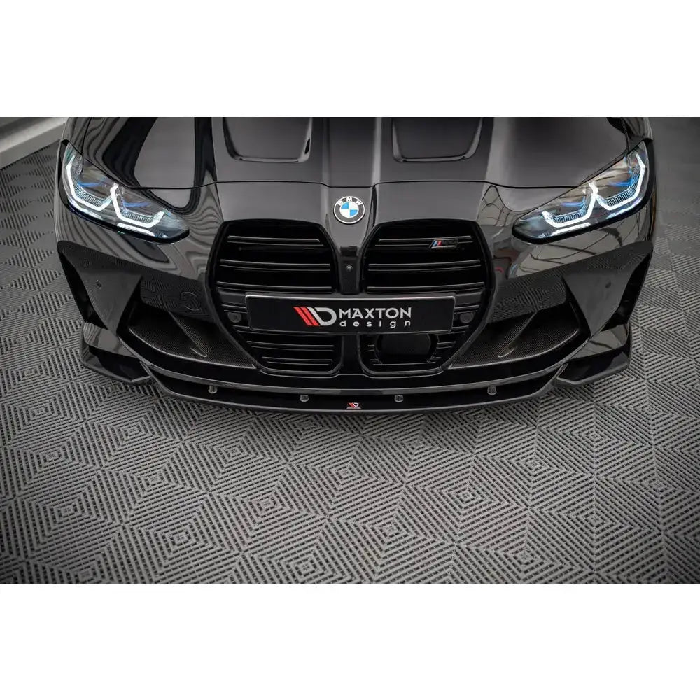 Front lip på BMW M4 G82 med sort, blank spoiler fra Maxton Design, sett forfra med LED-lykter.