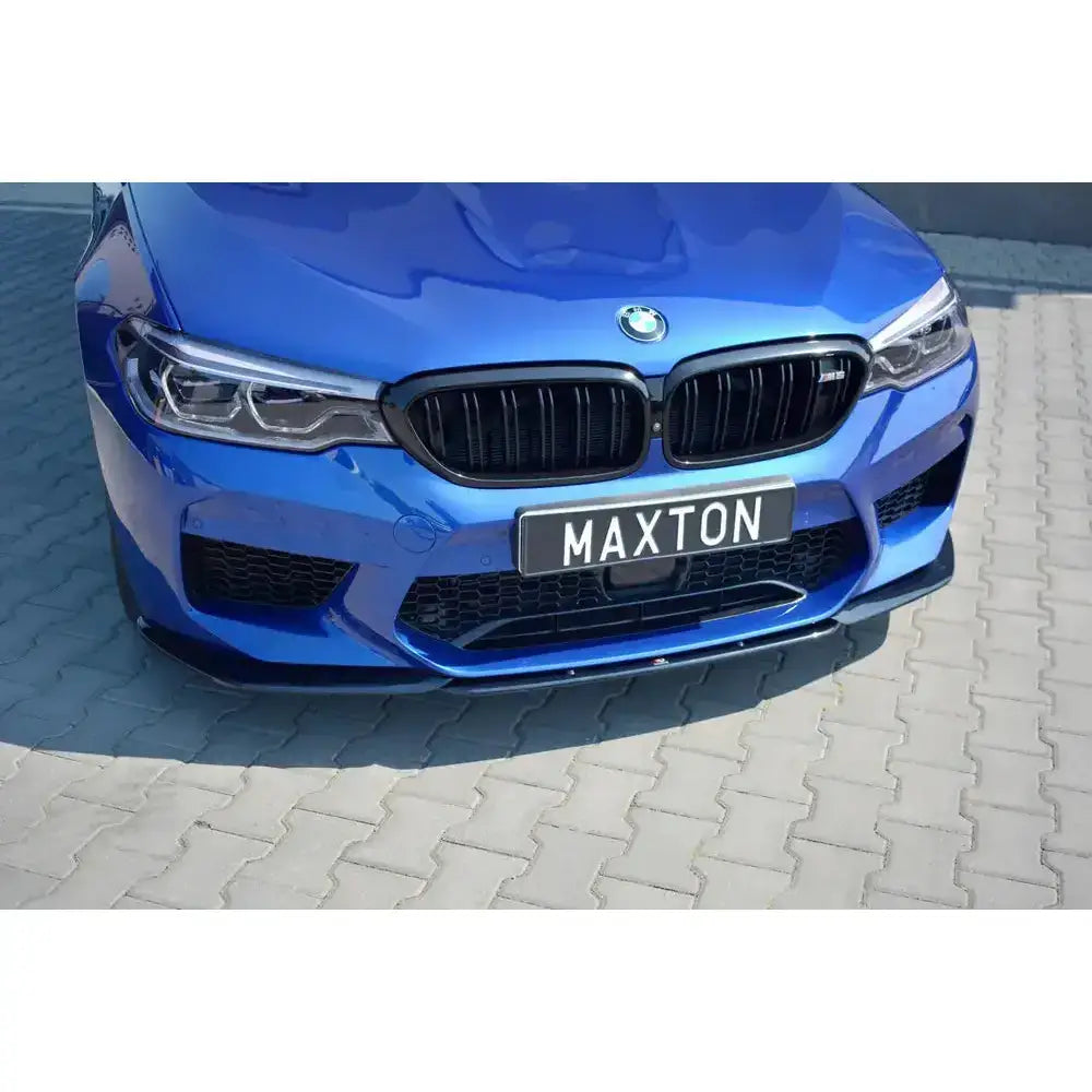 Front lip på Bmw M5 F90 V.2, blå bil med svart frontsplitter og Maxton-skilt på grå brostein.