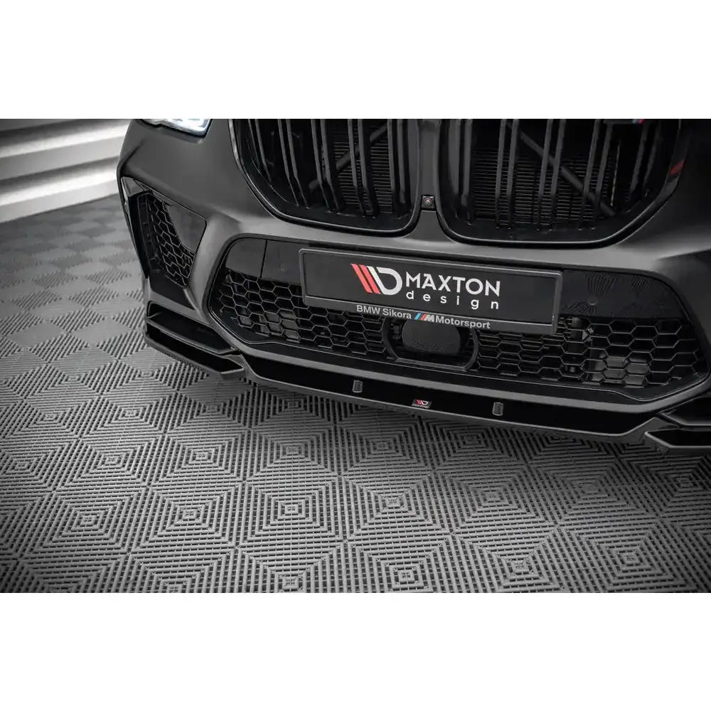 Front lip på BMW X5M F95 V.2 med Maxton Design-skilt, sett rett forfra på mønstret gulv.