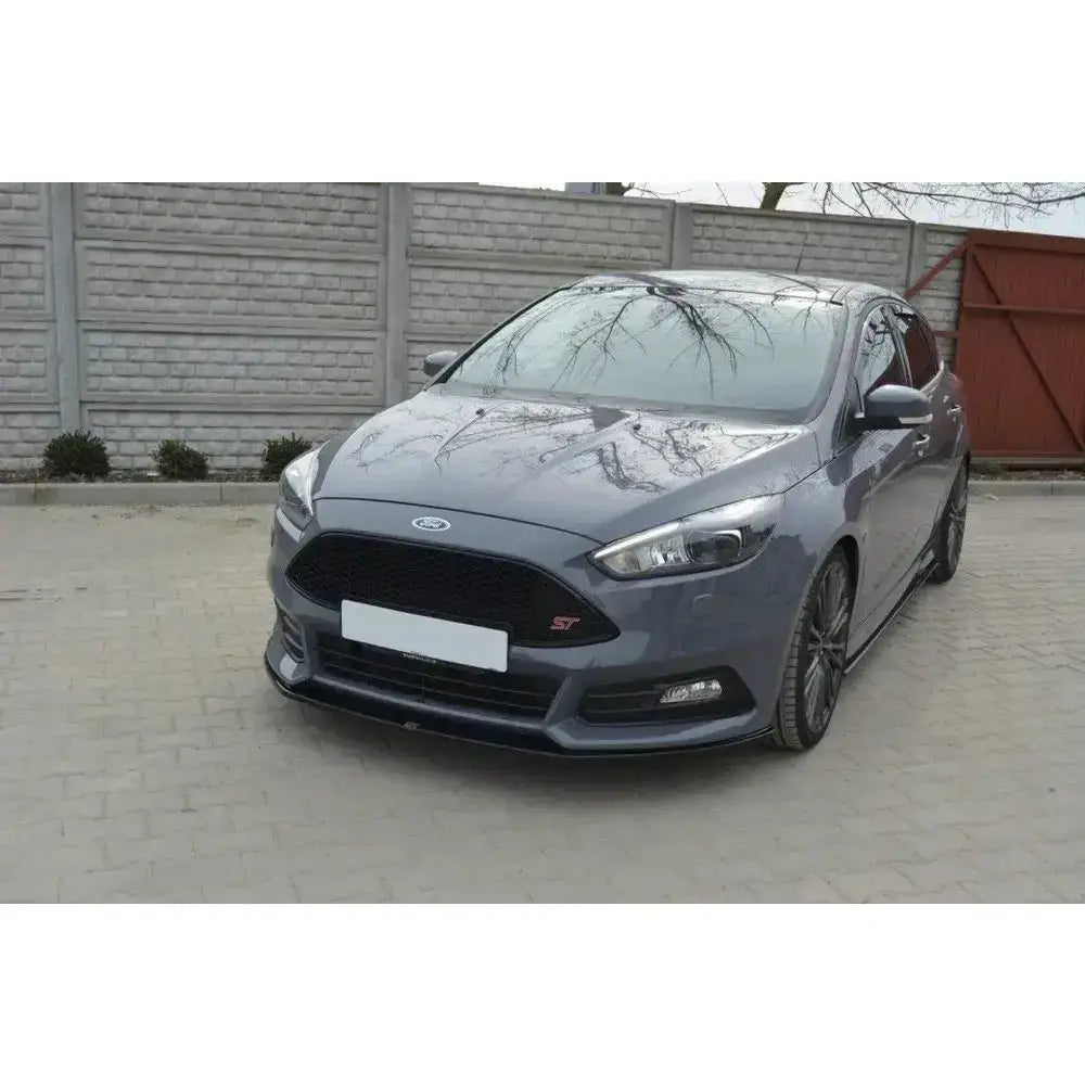 Frontspoiler på Ford Focus ST Mk3 Facelift med mørke felger og sort grill utendørs.
