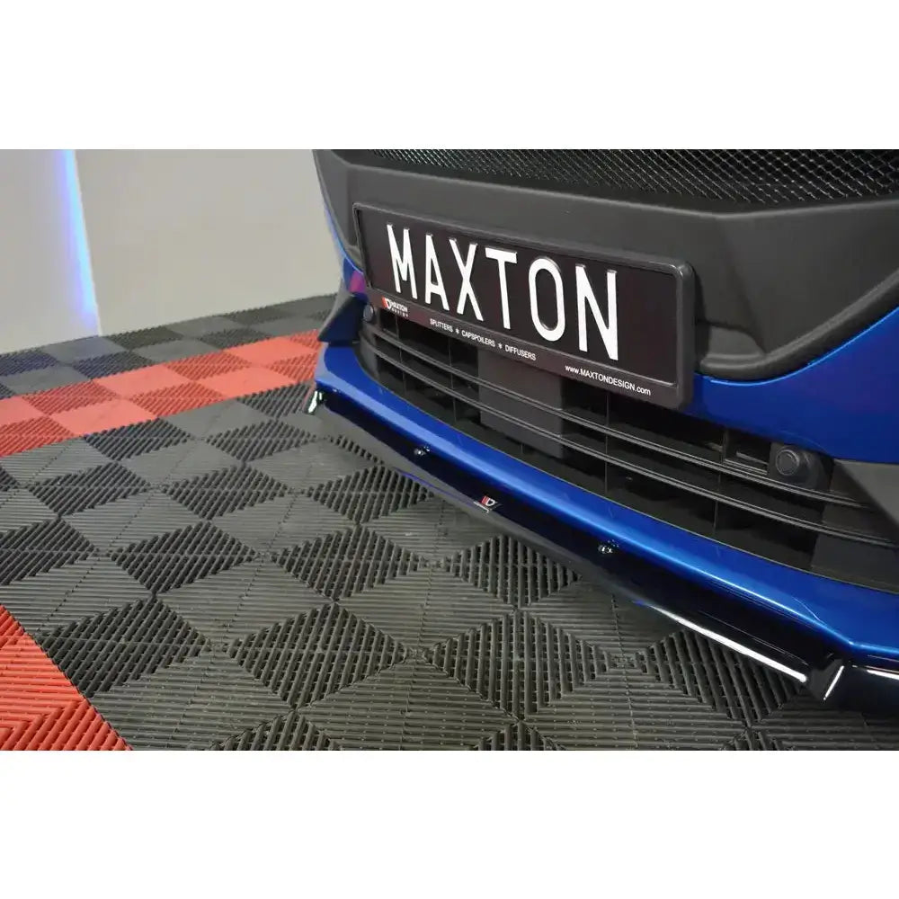 Front lip på blå Ford Focus ST med svart frontsplitter og "MAXTON"-skilt på mønstret gulv.