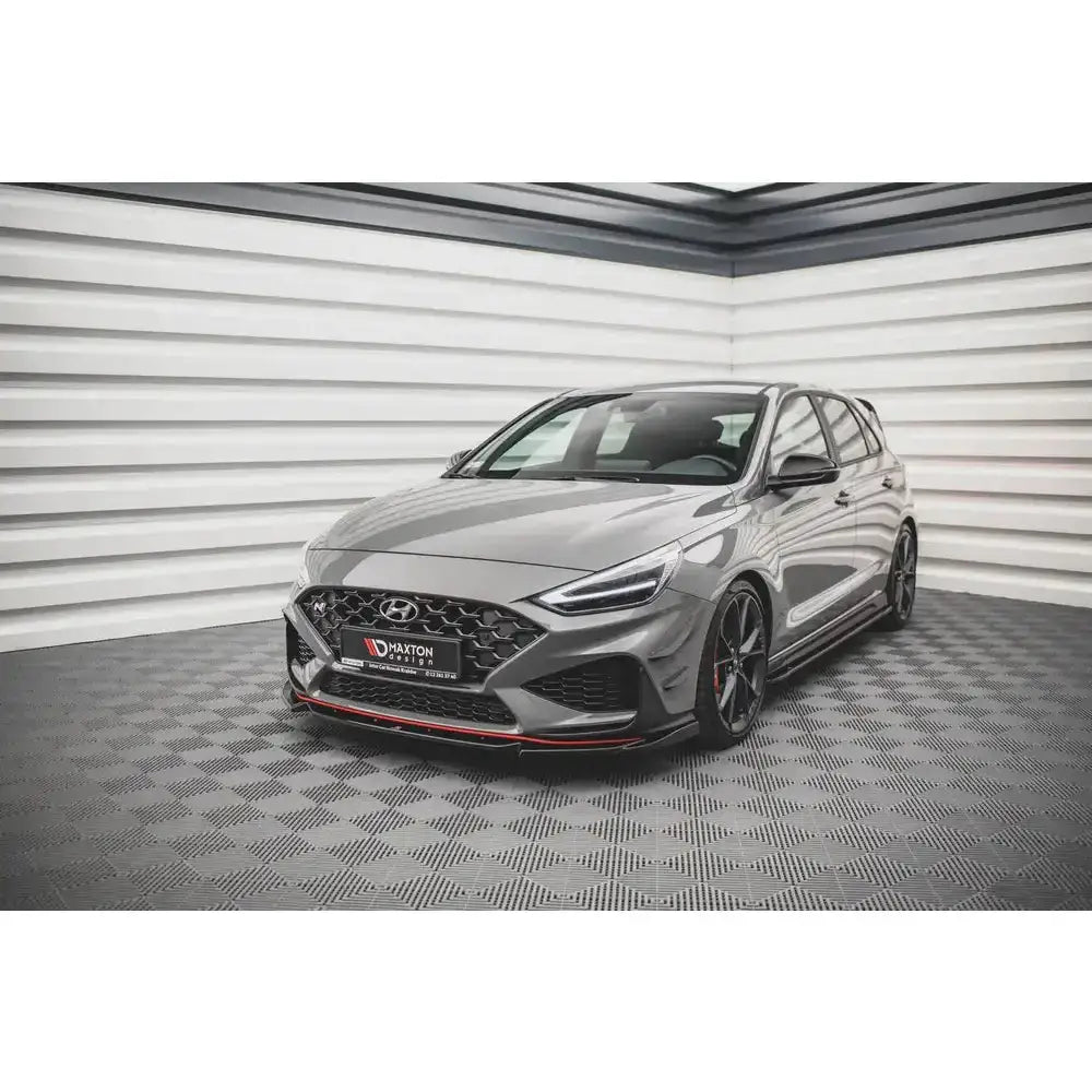 Front lip på Hyundai I30 N Hatchback Mk3, grå bil med røde detaljer og svarte felger innendørs.