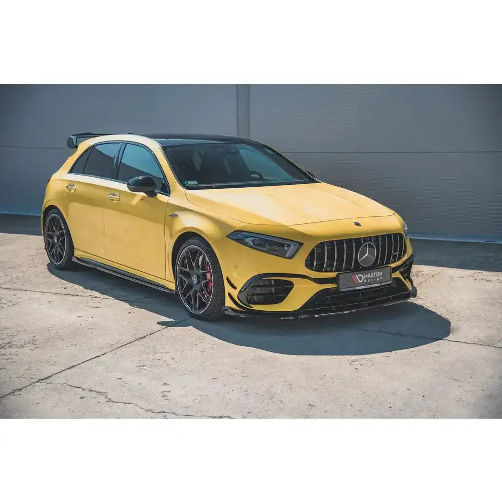 Frontspoiler på gul Mercedes-AMG A 45 S W177 med sorte detaljer og sportslige felger, sett skrått forfra.