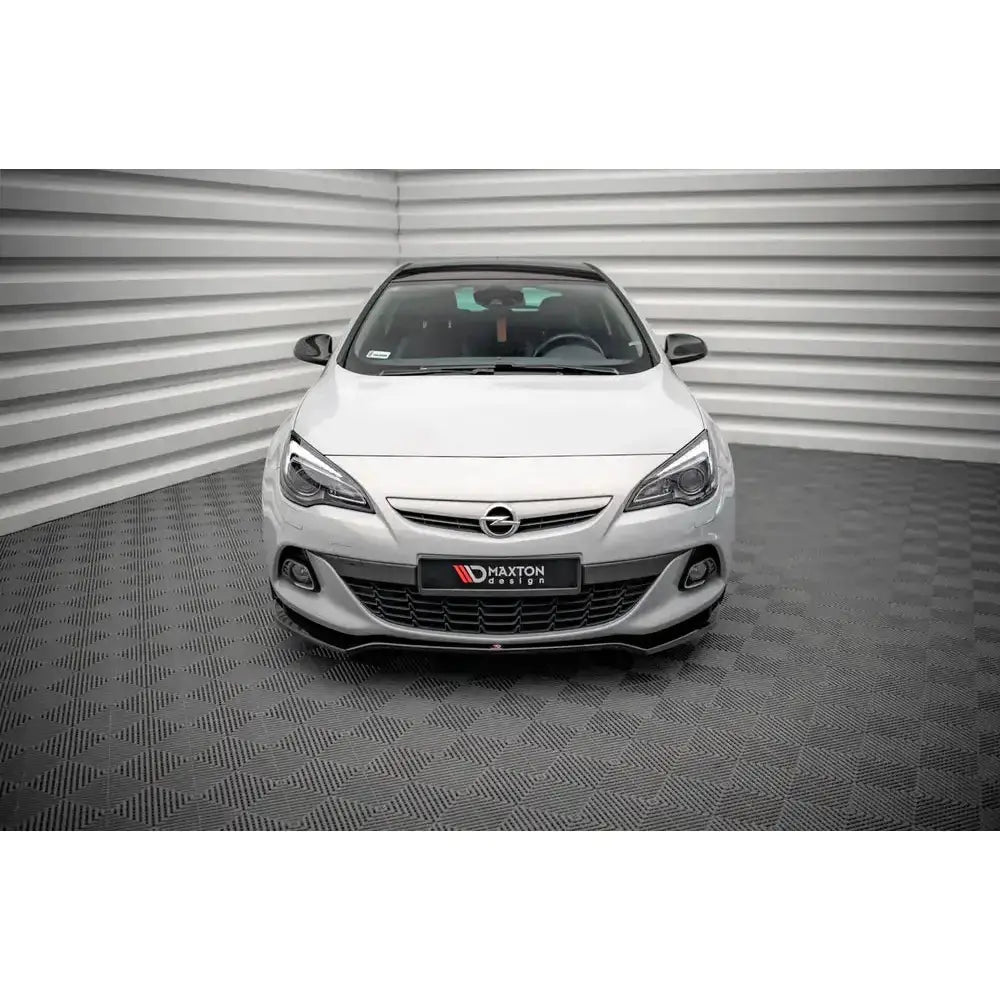 Frontspoiler på hvit Opel Astra GTC OPC-Line J 11-18 med sorte detaljer, sett forfra i lyst rom.