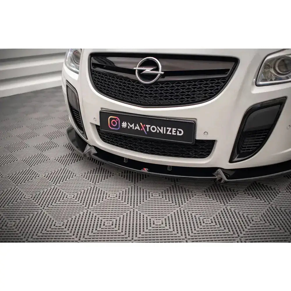 Frontsplitter til Opel Insignia OPC Mk1 V.2 montert på hvit bil med sort grill, sett forfra på grått gulv.